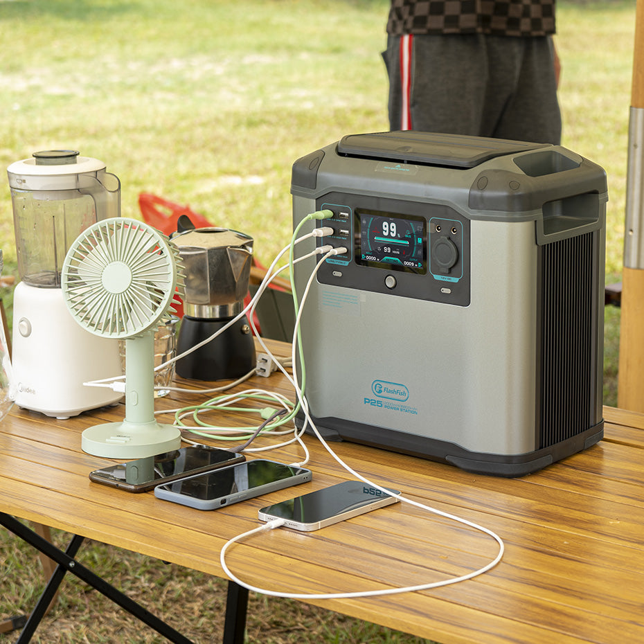 FlashFish P25 station on an outdoor table beside phones, a fan and a blender