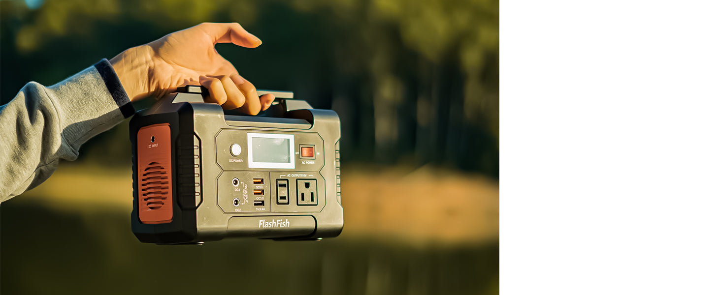 Person carrying a FlashFish portable power station outdoors against a wooded background