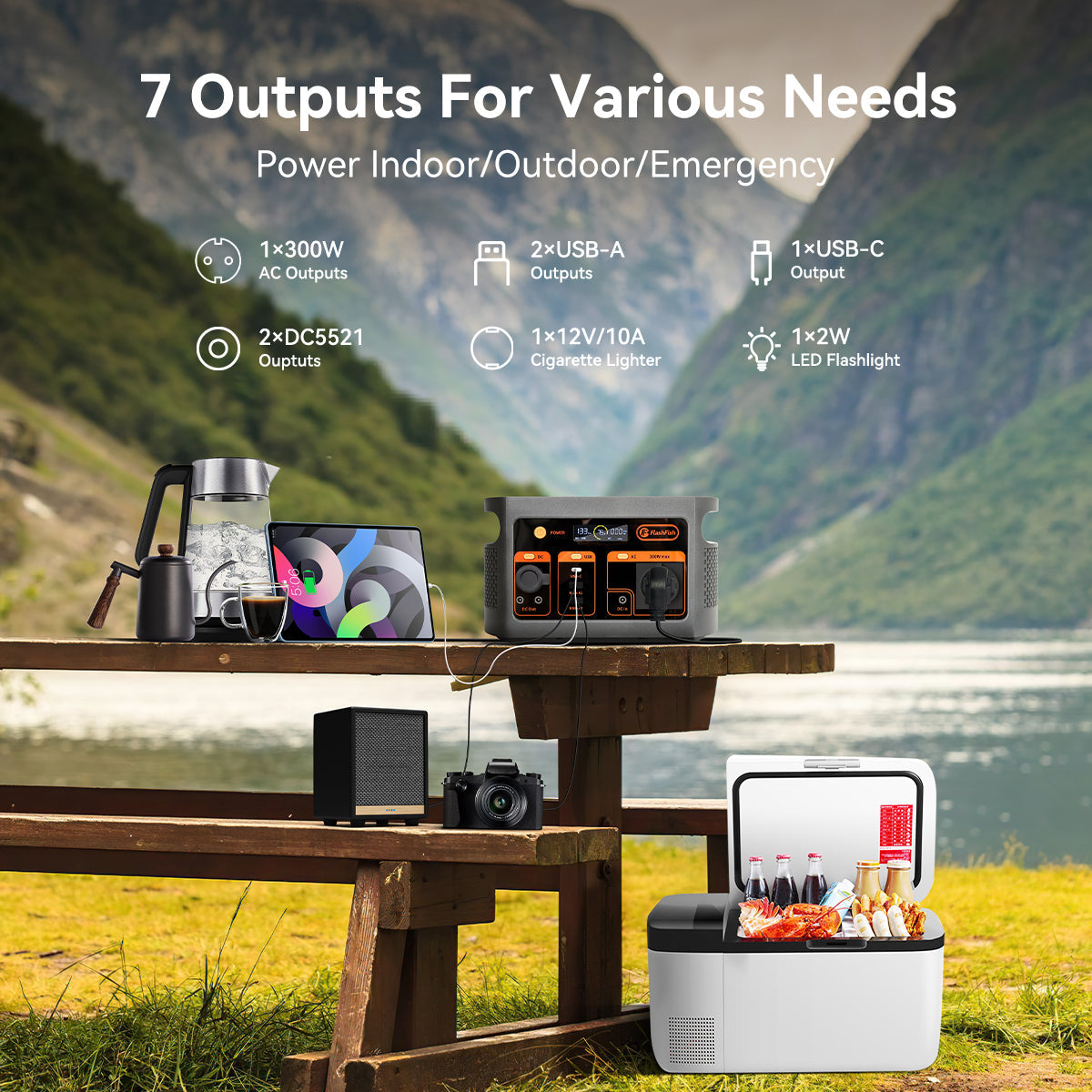 FlashFish E103 portable power station powering electronics on an outdoor table beside a cooler