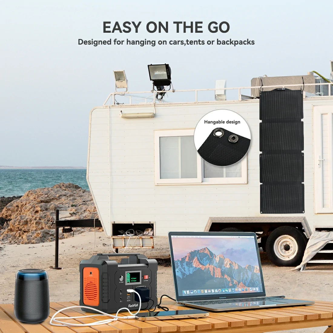 FlashFish E200 power station with a laptop and speaker beside a camper