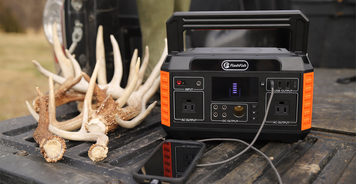Portable power station on an outdoor vehicle tailgate beside antlers.