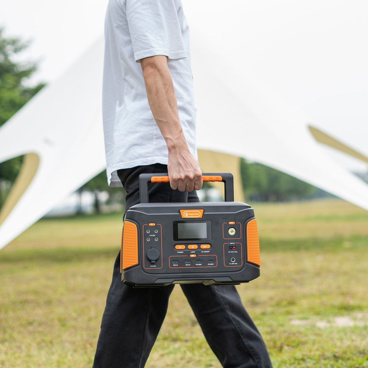Person carrying a black and orange FlashFish power station outdoors