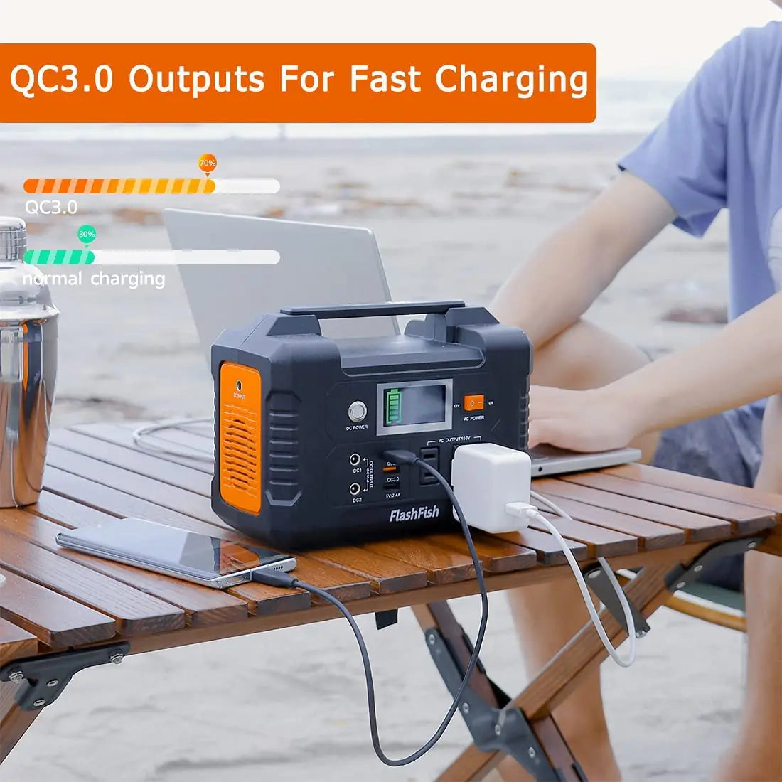 FlashFish E200 portable power station charging laptop and phone at a camping table