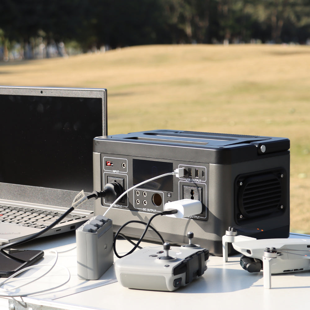 A portable power station sits on a table beside charging devices.