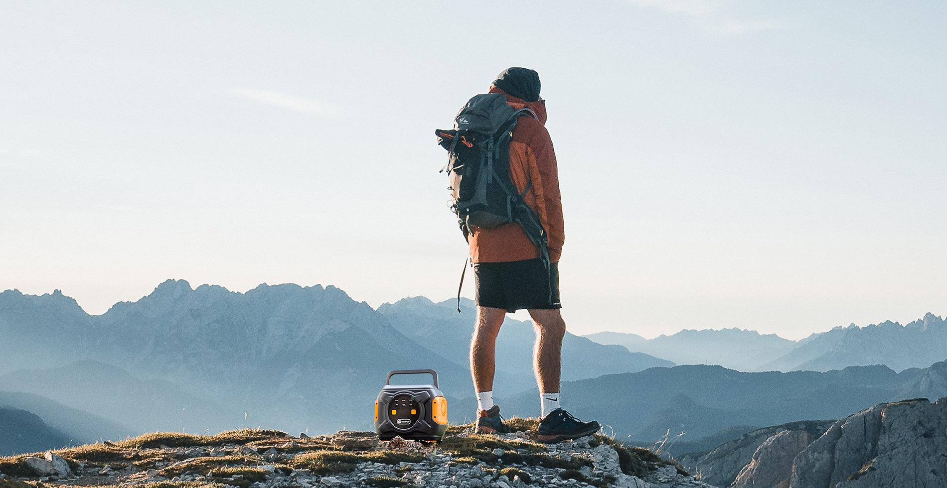 Hiker standing beside a portable power station in the mountains