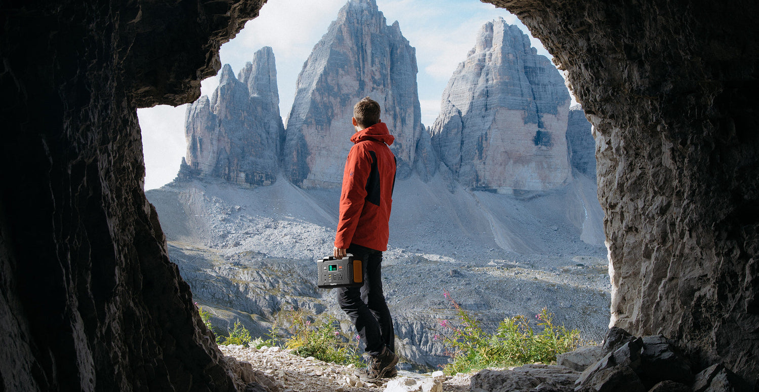 Hiker carrying a FlashFish E200 portable power station in a mountain setting